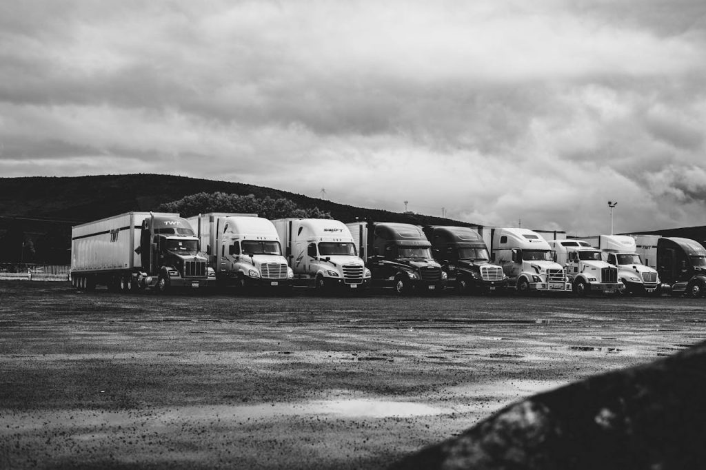 pexels photo 2348359 Row of parked semi trucks in a rainy lot, captured in a dramatic black and white setting.
